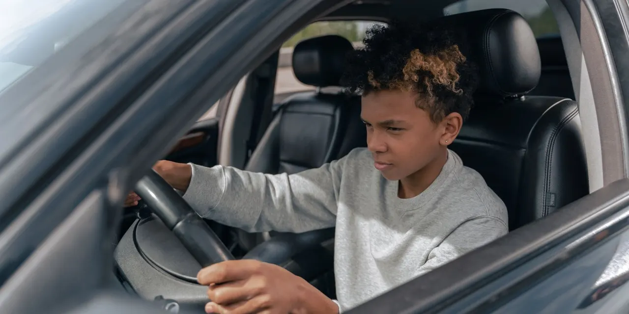 Personne réservant un rendez vous permis en ligne sur ordinateur, calendrier et clés de voiture sur le bureau.